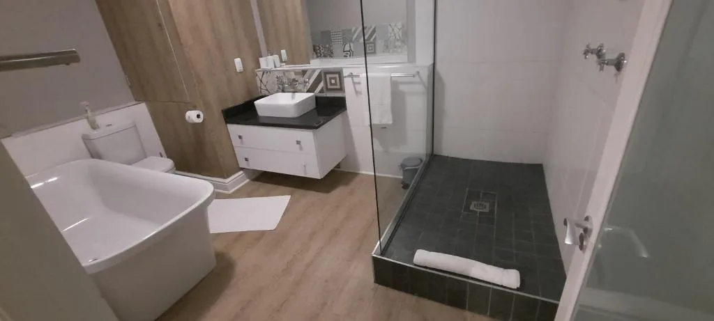 Modern bathroom with toilet, vessel sink, and dark tile shower area