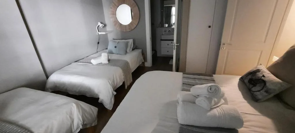 Clean modern bedroom with multiple single beds and round mirror above vanity