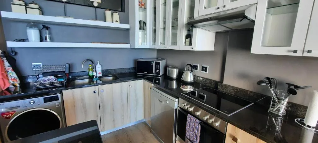 Modern kitchen with white cabinetry, black countertops, and stainless steel appliances