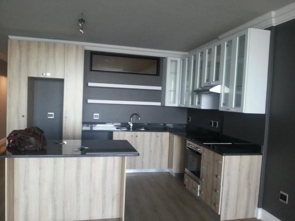 Modern kitchen with black countertops, wood cabinetry, and stainless steel appliances