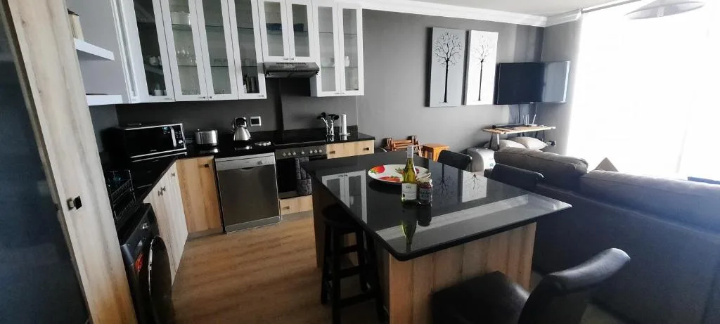 Modern kitchen with black countertops, stainless steel appliances, and white cabinetry
