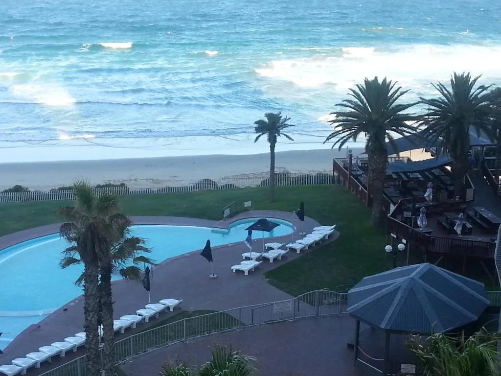 Ocean and beach view with pool and palm trees in foreground
