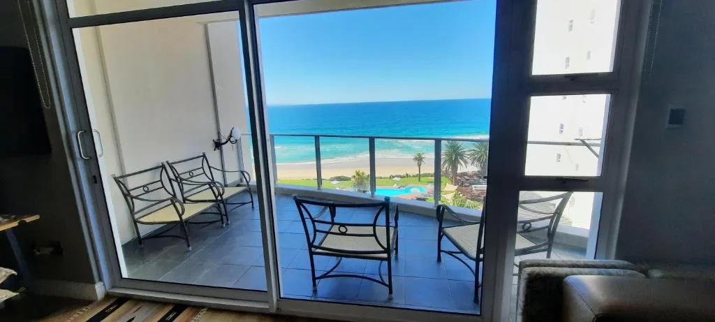 Ocean and beach vista from balcony with sea, sand, and palm trees
