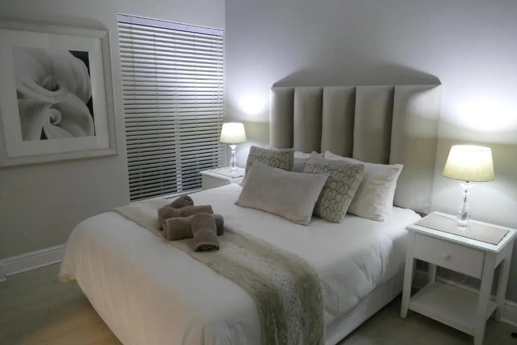 Elegant bedroom with upholstered headboard, white bedding, and side lamps