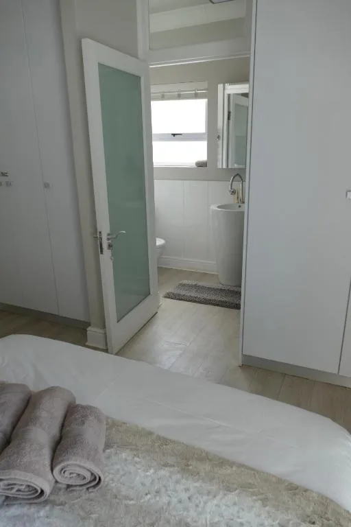 Bright bedroom with bed and open ensuite bathroom visible through doorway