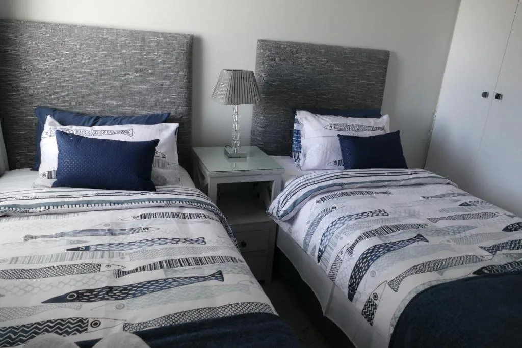 Twin bedroom with patterned bedding, navy pillows, and modern gray headboards