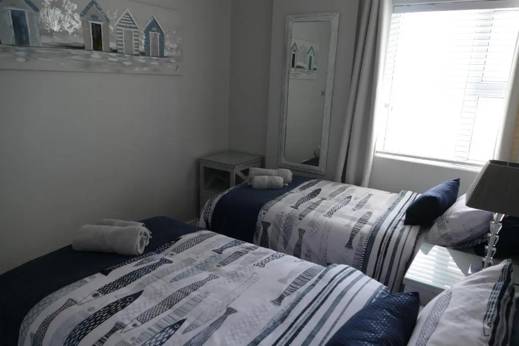 Twin bedroom with patterned bedding, rolled towels, and coastal decor