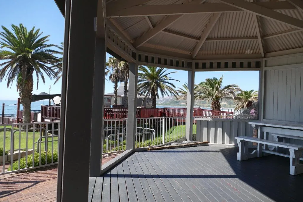 Covered wooden deck with ocean views, palm trees, and outdoor seating areas