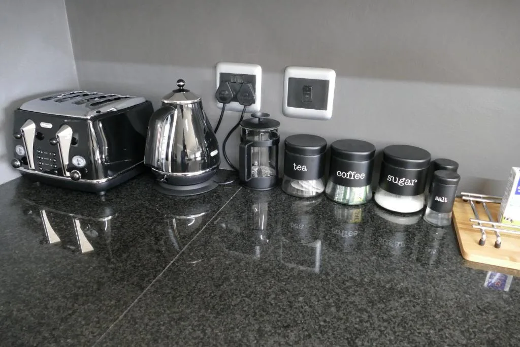 Kitchen countertop with appliances, kettle, coffee maker, and storage containers