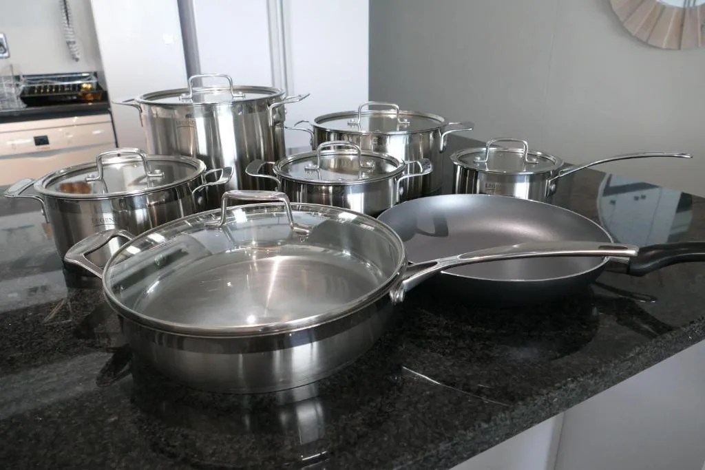 Stainless steel cookware set displayed on dark kitchen countertop