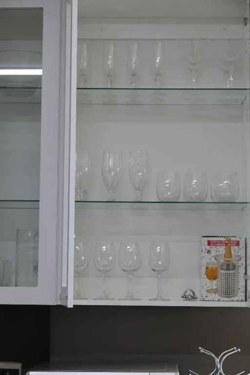 Glass cabinet displaying collection of wine glasses and beverage accessories