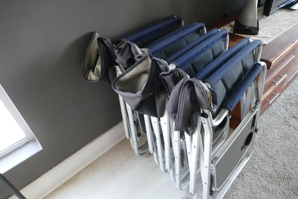 Stacked folding beach chairs with navy cushions stored indoors
