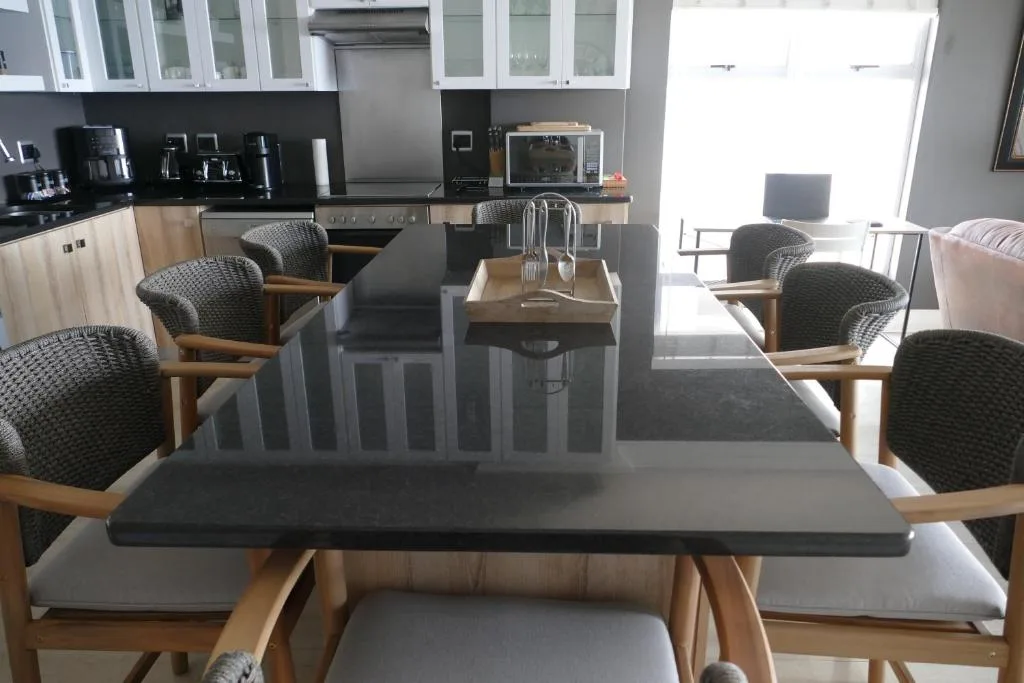 Modern dining table with wooden chairs and kitchen visible behind