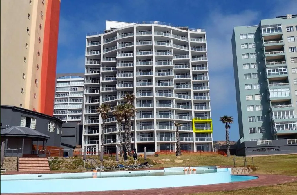 Modern apartment building with balconies overlooking landscaped grounds and pool