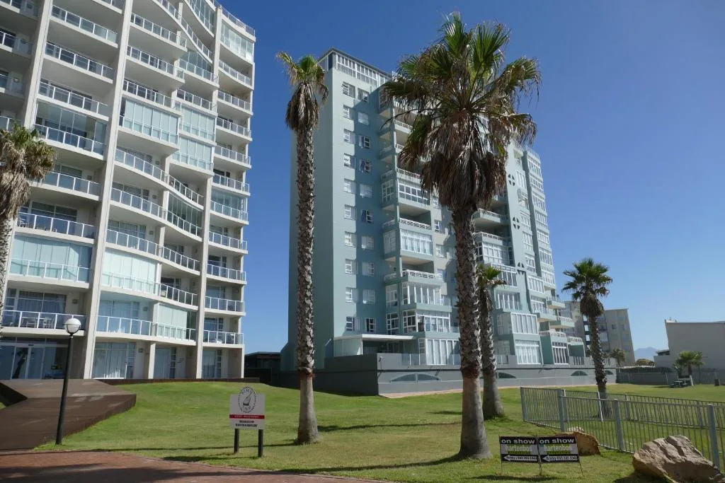 Modern apartment buildings with palm trees and manicured lawns under blue sky