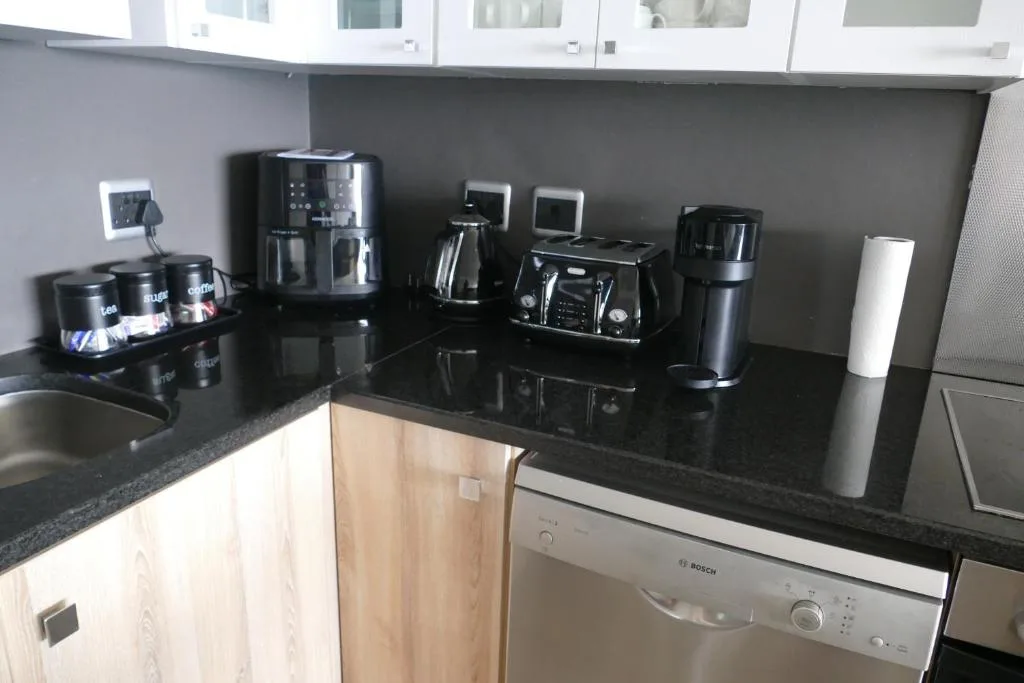 Modern kitchen with black countertops, appliances, and white cabinetry