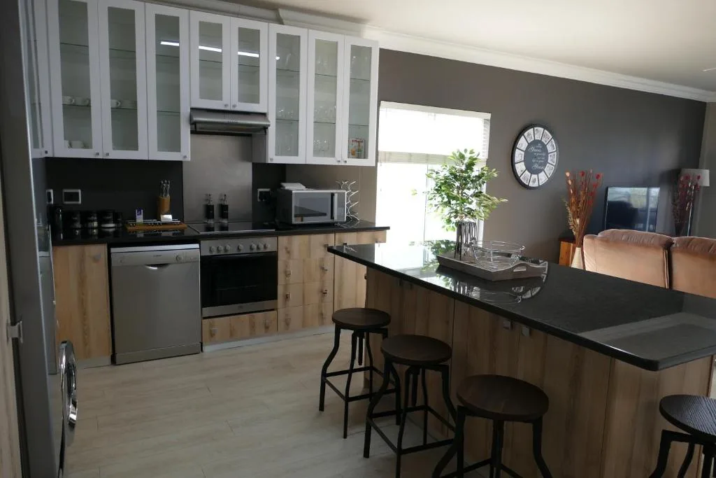 Modern kitchen with white cabinetry, black countertops, and island seating area