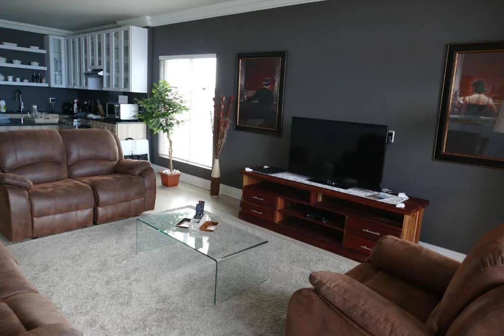 Modern living room with leather sofas, flat-screen TV, and open kitchen