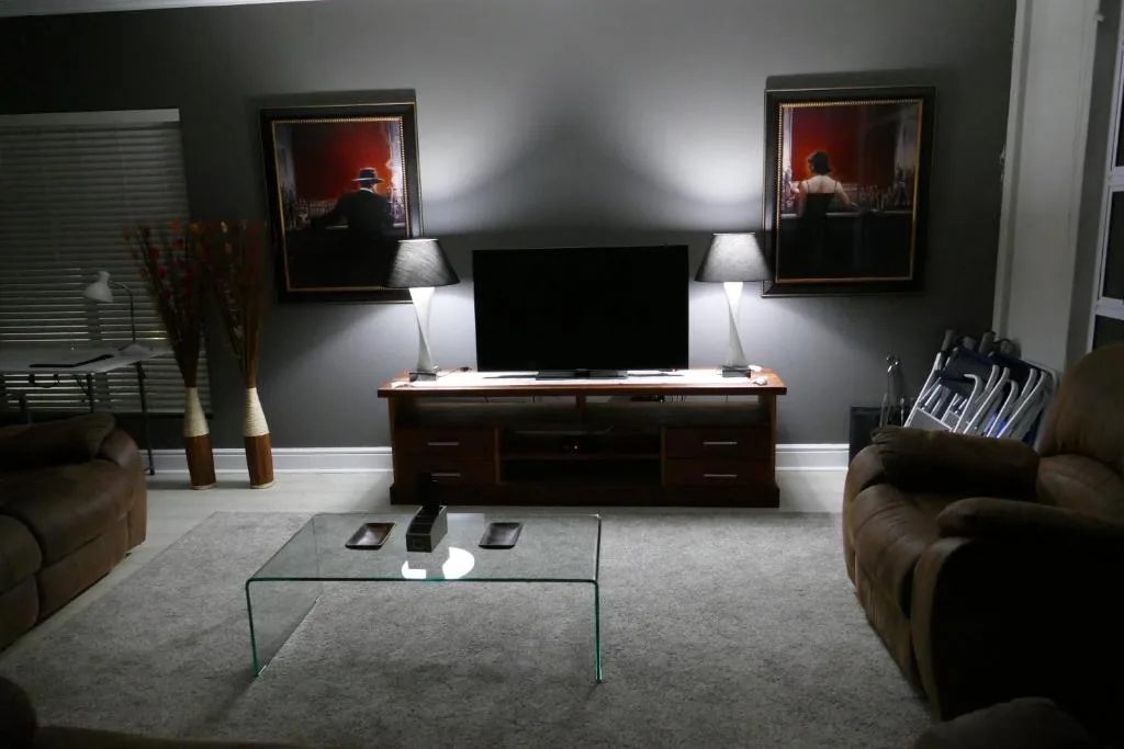 Modern lounge with brown leather sofa, TV unit, and framed artwork on walls