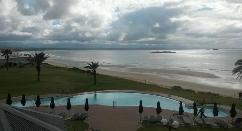 Curved swimming pool overlooking pristine beach and ocean horizon