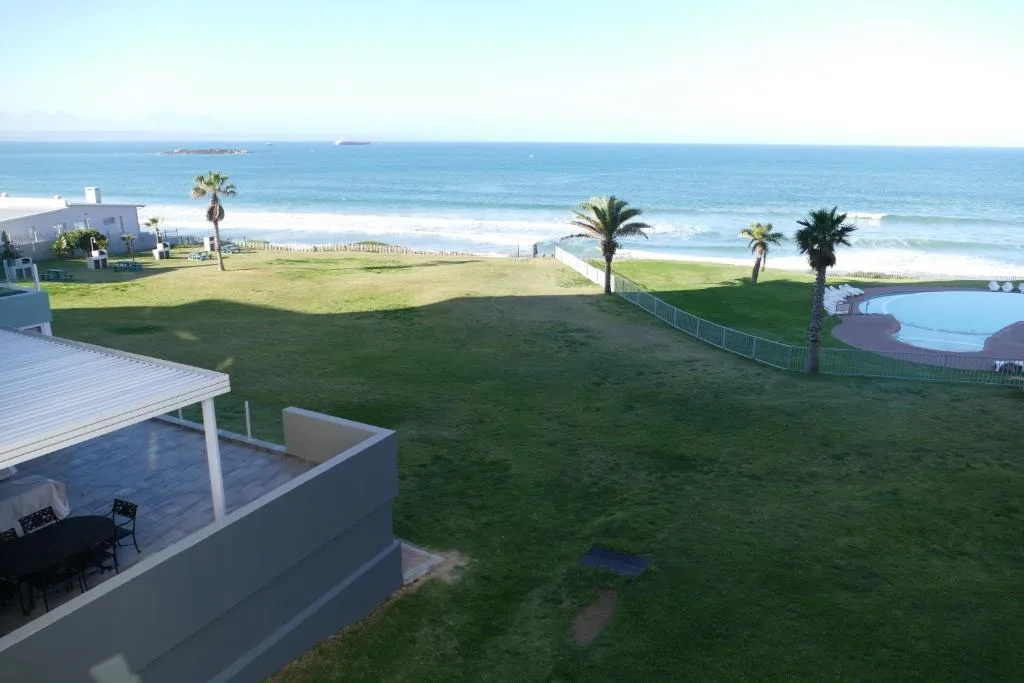 Ocean and beach vista with manicured lawn and palm trees
