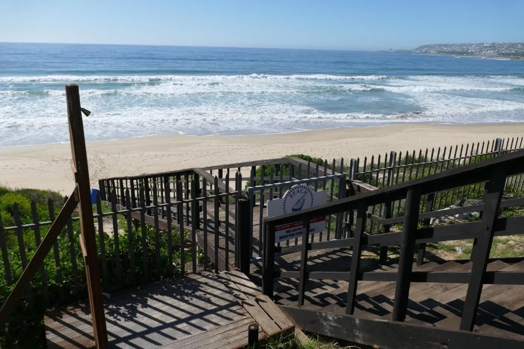 Panoramic ocean vista with sandy beach, rolling waves, and coastal settlements