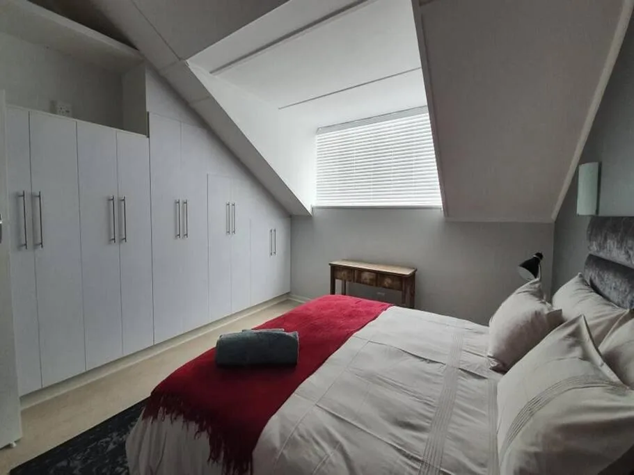 Modern bedroom with queen bed, red runner, white built-in wardrobes, skylights