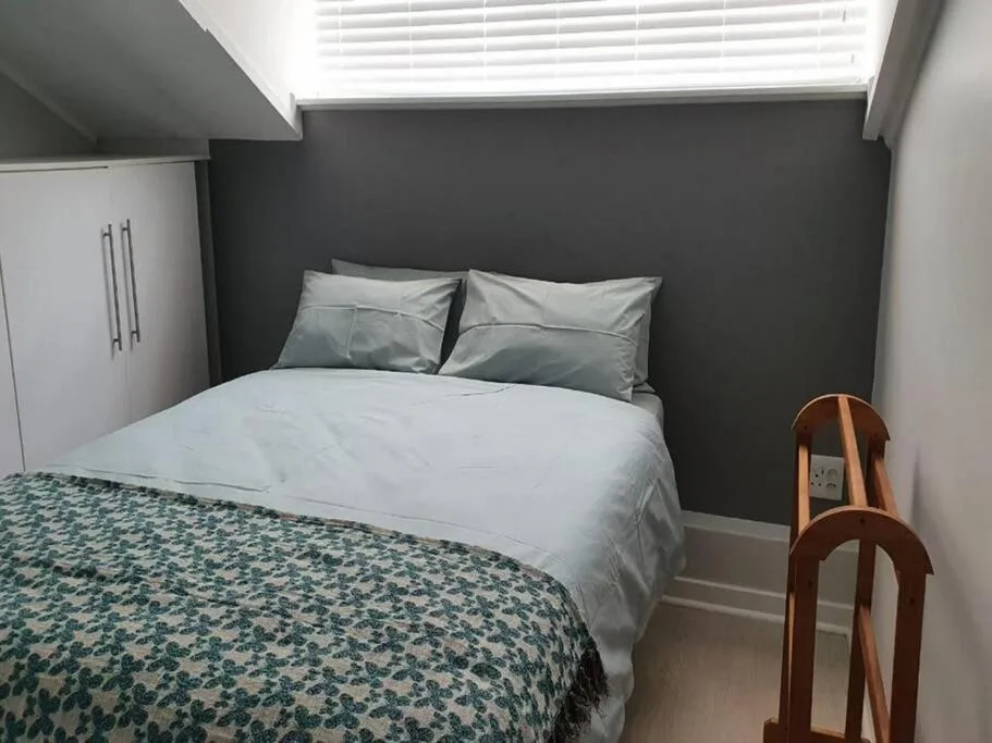Modern bedroom with queen bed, gray accent wall, white pillows, patterned throw