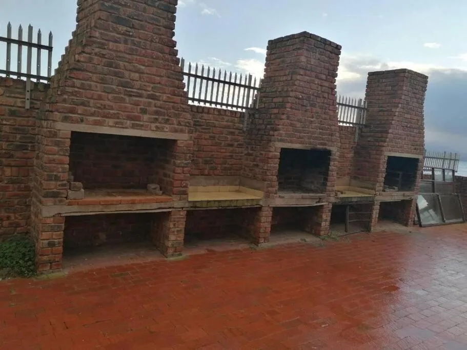 Outdoor braai area with multiple brick fireplaces and picket fence