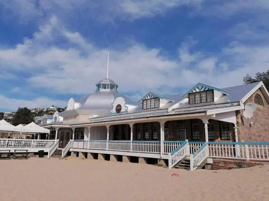 Distinctive beachfront building with white railings and domed roof on sandy beach