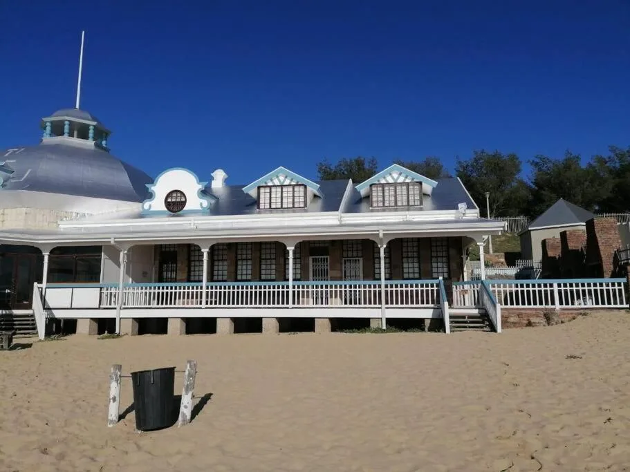 Beachfront property with white facade and wraparound deck overlooking sandy beach