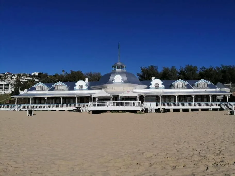 Elegant white beachfront pavilion with distinctive dome and covered veranda on sandy beach