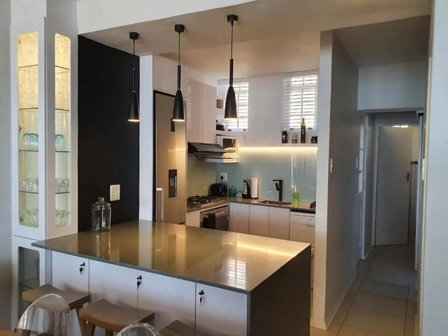 Modern kitchen with black pendant lights, white cabinetry, and dark countertop island