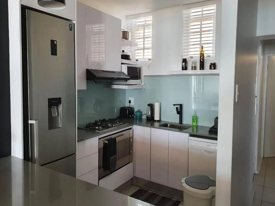 Modern kitchen with stainless steel appliances and turquoise glass backsplash