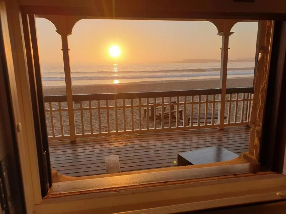 Sunrise over the ocean viewed from a beachfront deck with railings