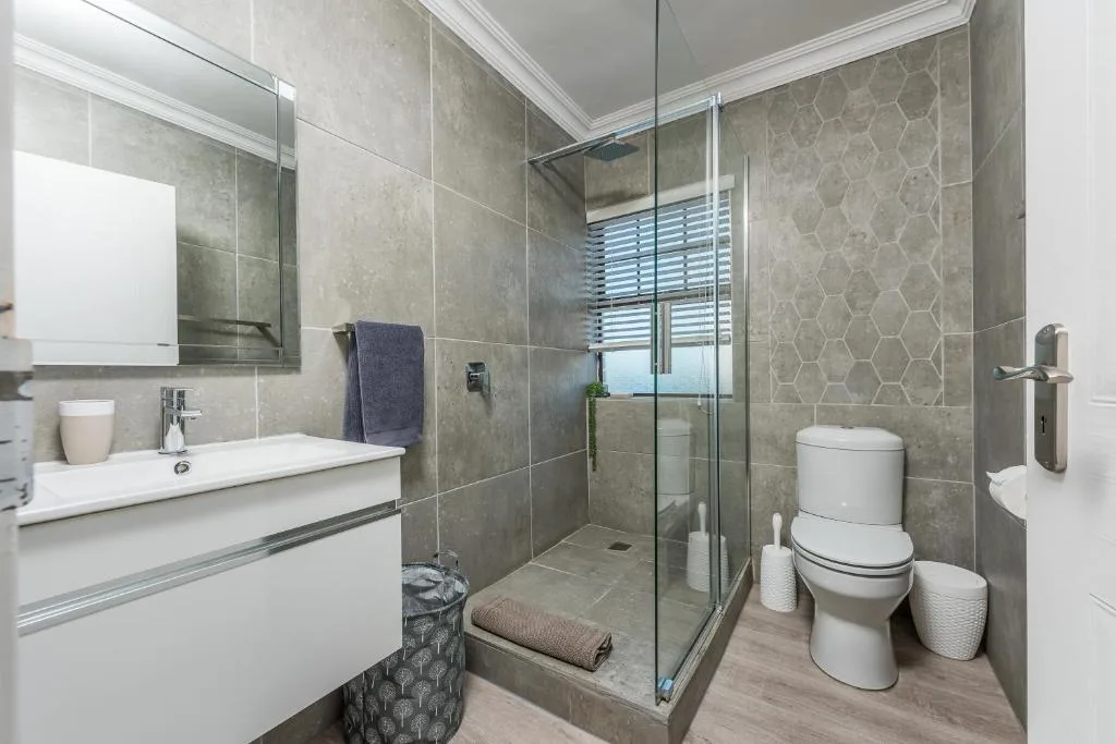 Modern bathroom with walk-in shower, white vanity, and toilet fixtures
