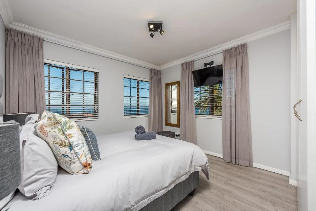 Spacious bedroom with queen bed, ocean views, and wall-mounted television