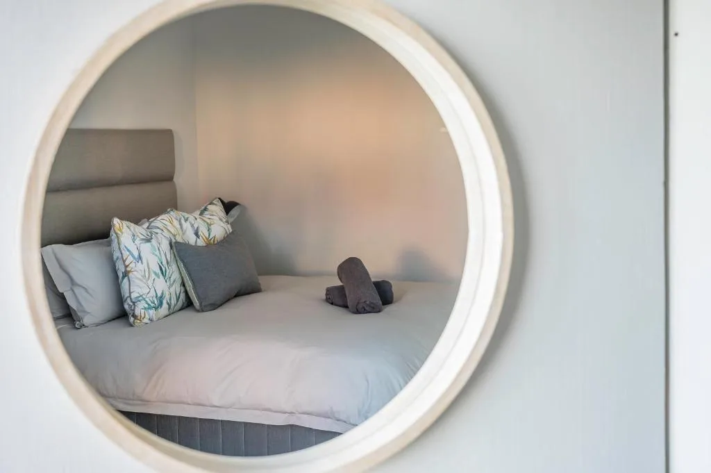 Modern circular window framing a cozy bed with decorative pillows and bedding