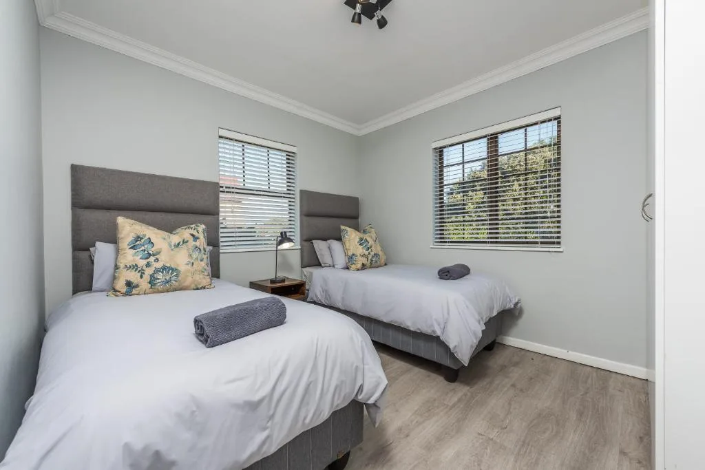 Twin bedroom with two single beds, grey upholstered headboards, patterned cushions