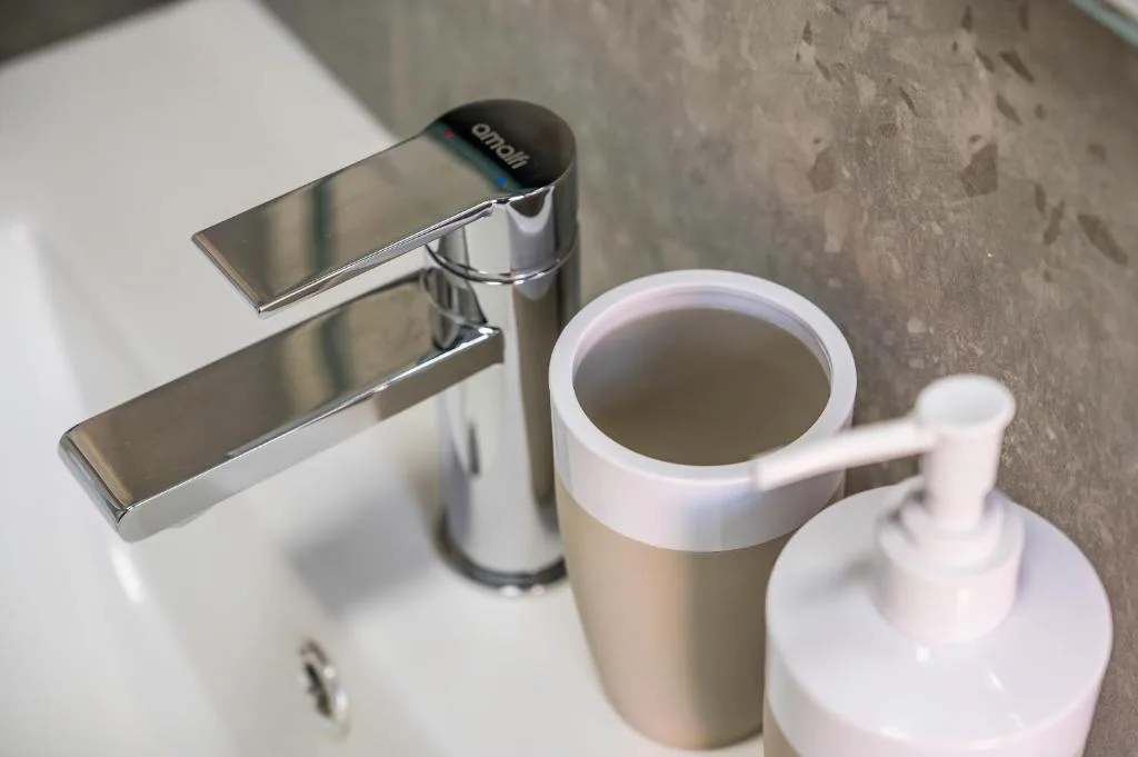 Modern chrome bathroom tap with soap dispenser and amenities