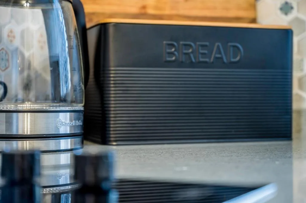 Close-up of kitchen countertop with blue bread bin and kettle