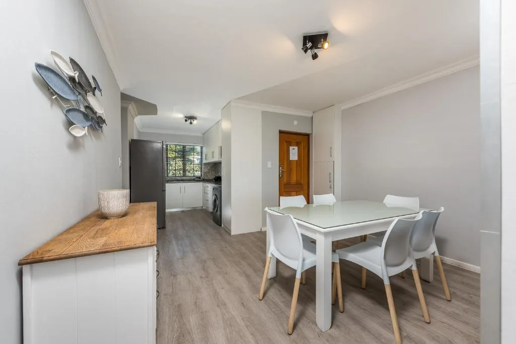 Modern dining table with white chairs in open-plan kitchen area