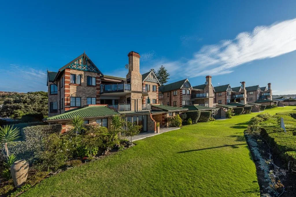 Victorian-style stone buildings with manicured gardens and green lawns