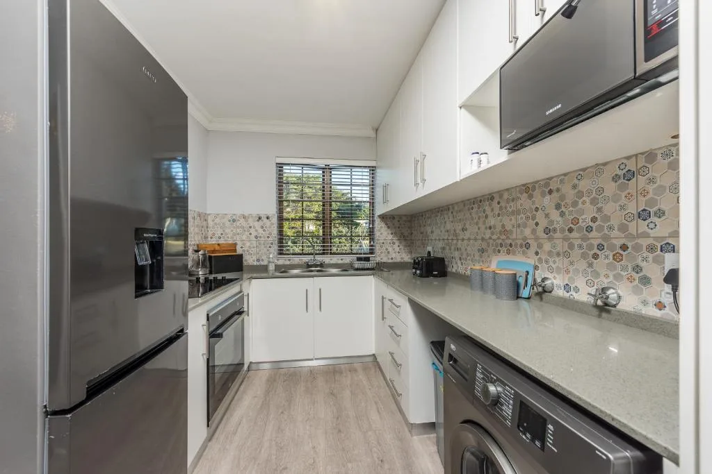 Modern kitchen with white cabinetry, stainless steel appliances, patterned backsplash tiles