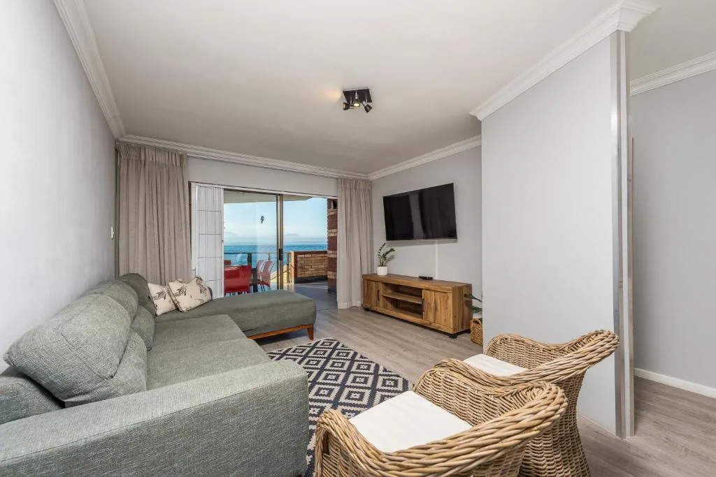 Spacious lounge with grey sofa, TV, ocean view through glass doors