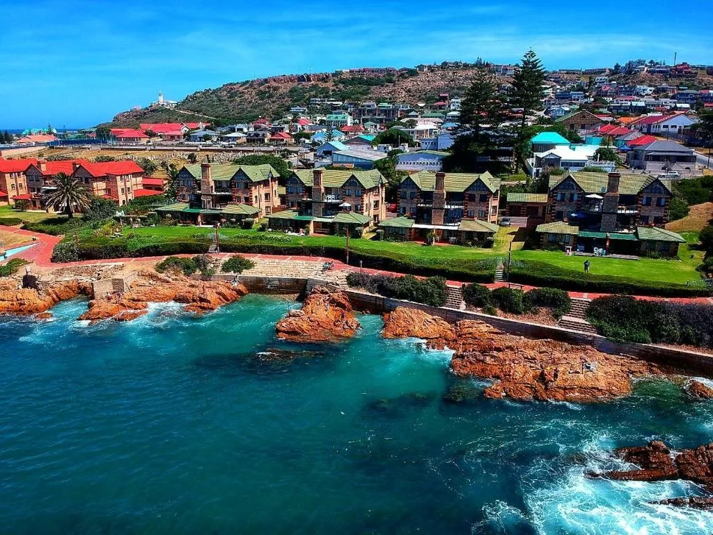 Turquoise ocean and rocky coastline with colorful beachfront properties on lush hillside