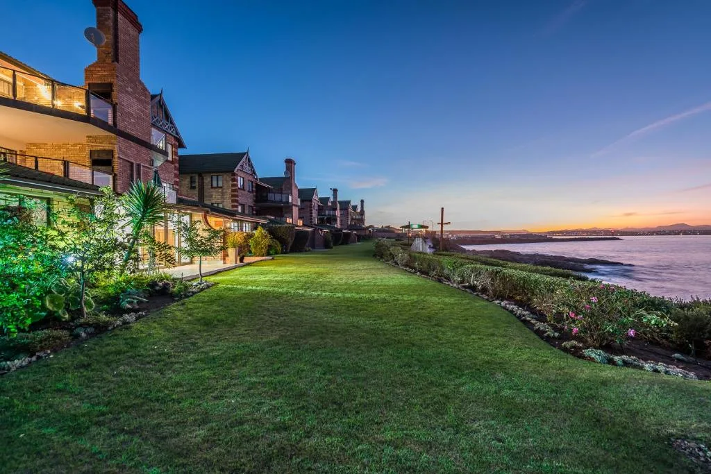Waterfront properties with manicured lawns overlooking tranquil lagoon at sunset