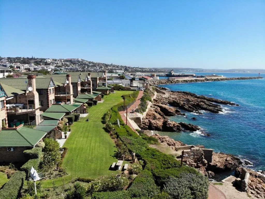 Coastal property overlooks rocky shoreline and turquoise ocean waters