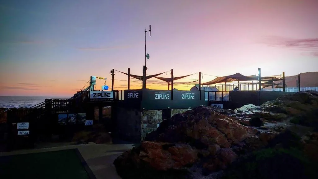 Sunset view over ocean with zipline platform and rocky coastline