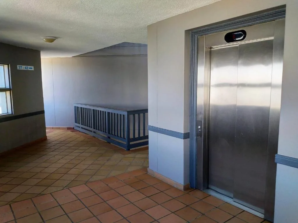Modern stainless steel elevator in building hallway with terracotta floor tiles